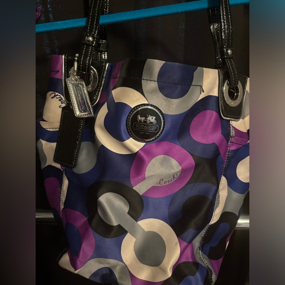 Coach multicolored logo fabric tote with outside end pockets.